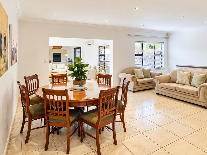 Spacious open-plan living and dining area featuring neutral tiled flooring, recessed lighting, and built-in cabinetry, offering a bright and versatile layout.