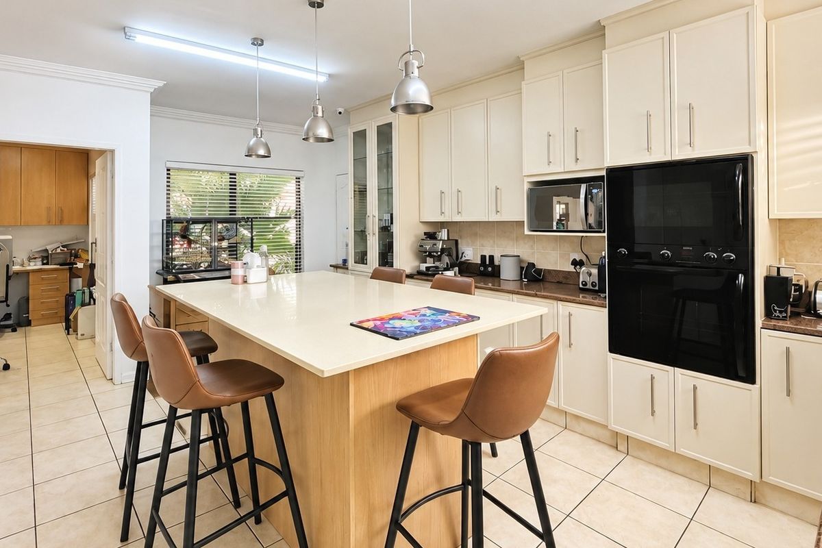 A well-appointed kitchen featuring a central island with stone countertops, built-in oven and microwave, ample cabinetry, and tiled flooring.