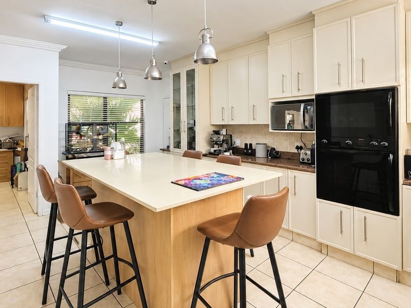 A well-appointed kitchen featuring a central island with stone countertops, built-in oven and microwave, ample cabinetry, and tiled flooring.