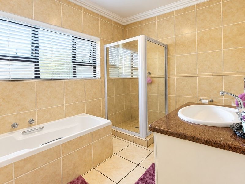 A well-maintained bathroom featuring a built-in bathtub, separate shower enclosure, and a vanity with a granite countertop and tiled finishes.