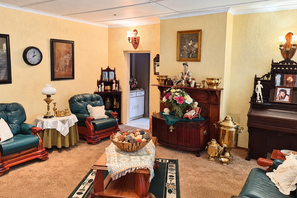 A traditional living room featuring a built-in fireplace mantel, wall sconces, and textured wall finishes, offering a classic layout with potential for modern updates.
