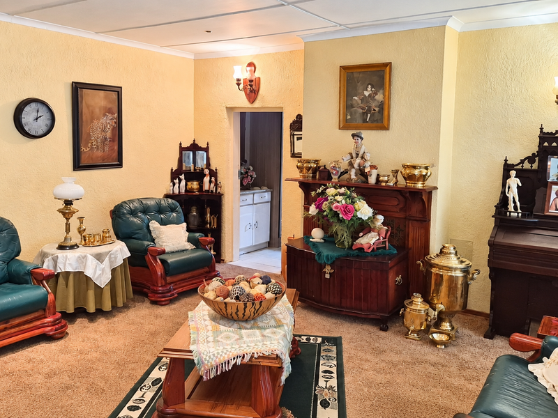 A traditional living room featuring a built-in fireplace mantel, wall sconces, and textured wall finishes, offering a classic layout with potential for modern updates.