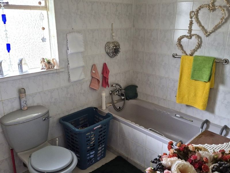 A functional bathroom featuring a bathtub, toilet, and fully tiled walls, offering a practical layout with natural light from the window.