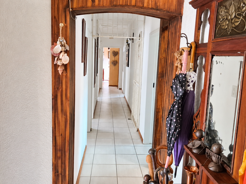 A bright hallway featuring tiled flooring and a decorative wooden archway leading to the interior living spaces.