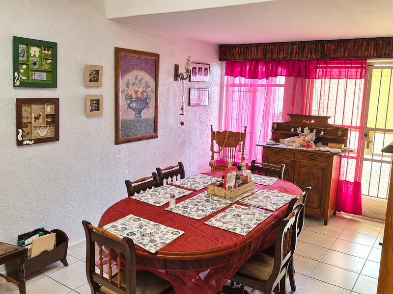 A dining room featuring tiled flooring, a wall-mounted light fixture, and direct access to an outdoor area through a security gate.