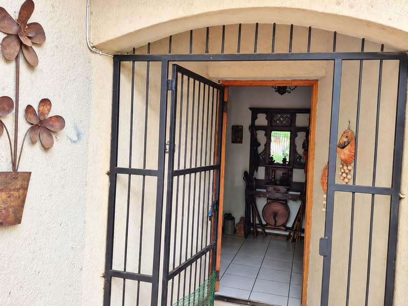 An arched entrance featuring a black metal security gate and tiled flooring, providing access to the interior of the home.