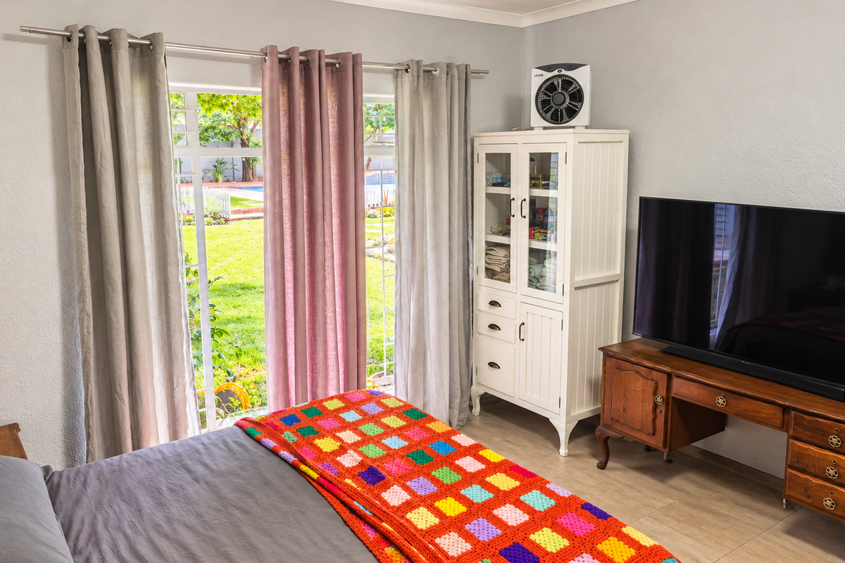 A well-lit bedroom featuring tiled flooring and a sliding glass door that provides direct access to the garden area.