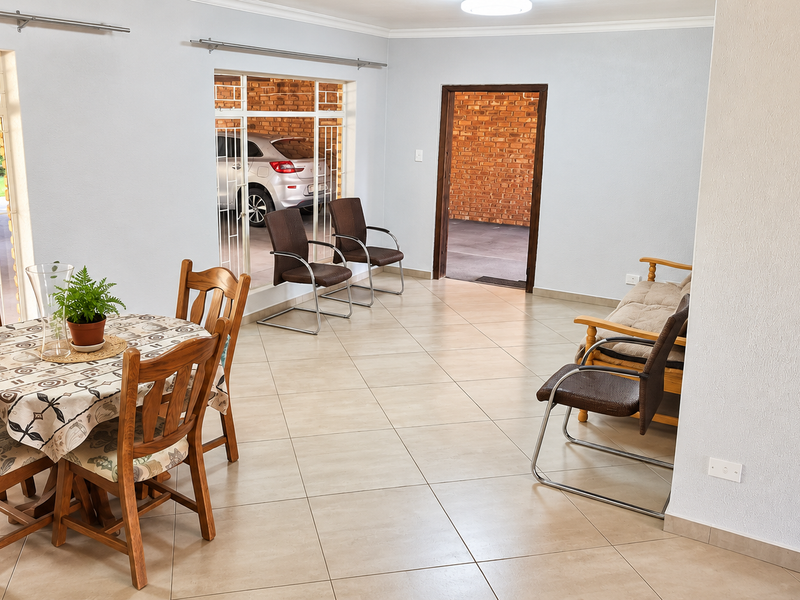 A spacious living area featuring neutral tiled flooring and large windows that provide natural light and views of the exterior brickwork.