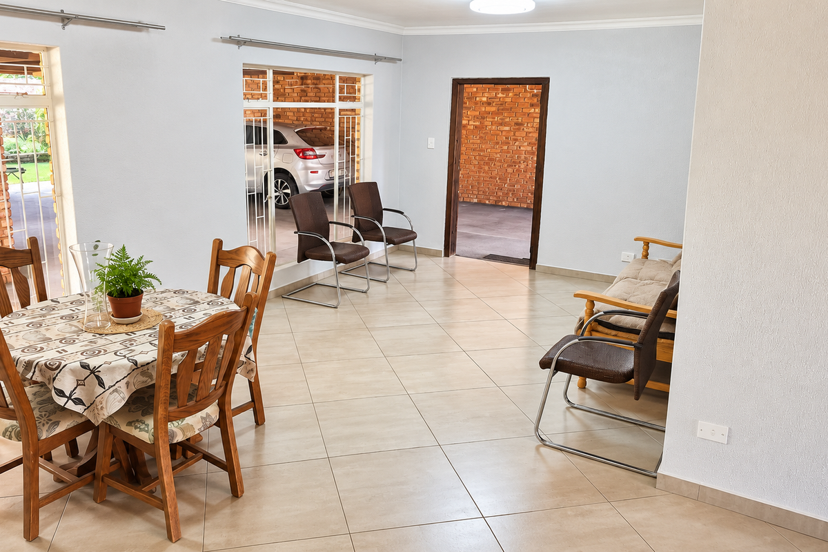 A spacious living area featuring neutral tiled flooring and large windows that provide natural light and views of the exterior brickwork.