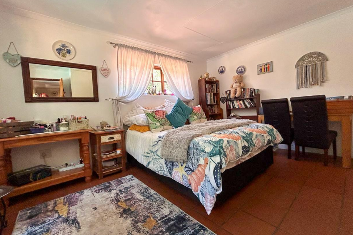 A cozy bedroom featuring terracotta tile flooring, coved ceiling cornicing, and a timber-framed window, offering a warm and traditional aesthetic.