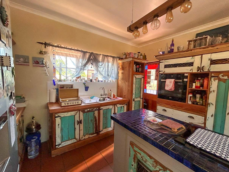 A rustic-style kitchen featuring custom painted cabinetry, tiled countertops, built-in oven, and terracotta floor tiles with warm pendant lighting.