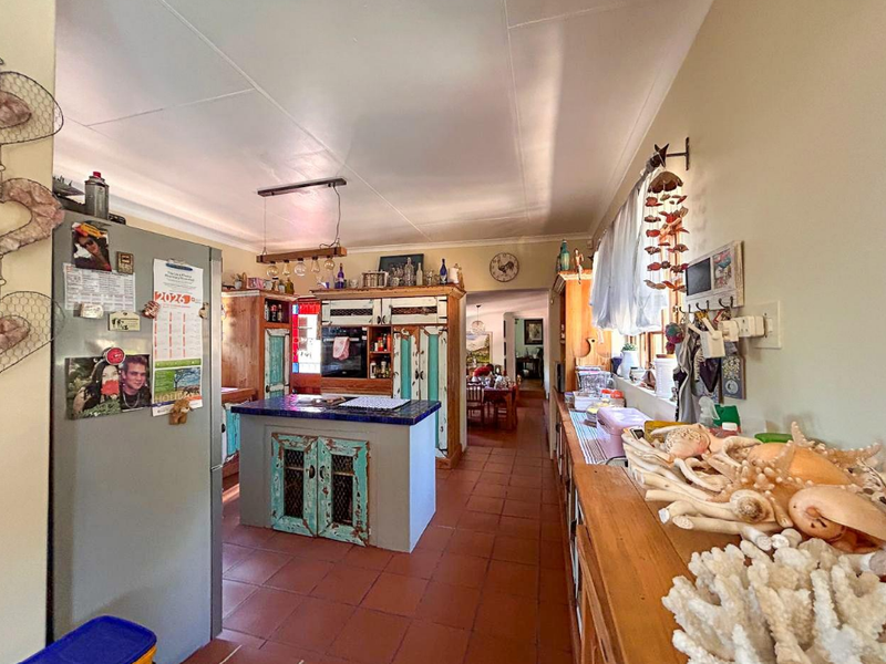 A rustic-style kitchen featuring a central island, built-in cabinetry, and terracotta tiled flooring, offering a warm and functional cooking space.