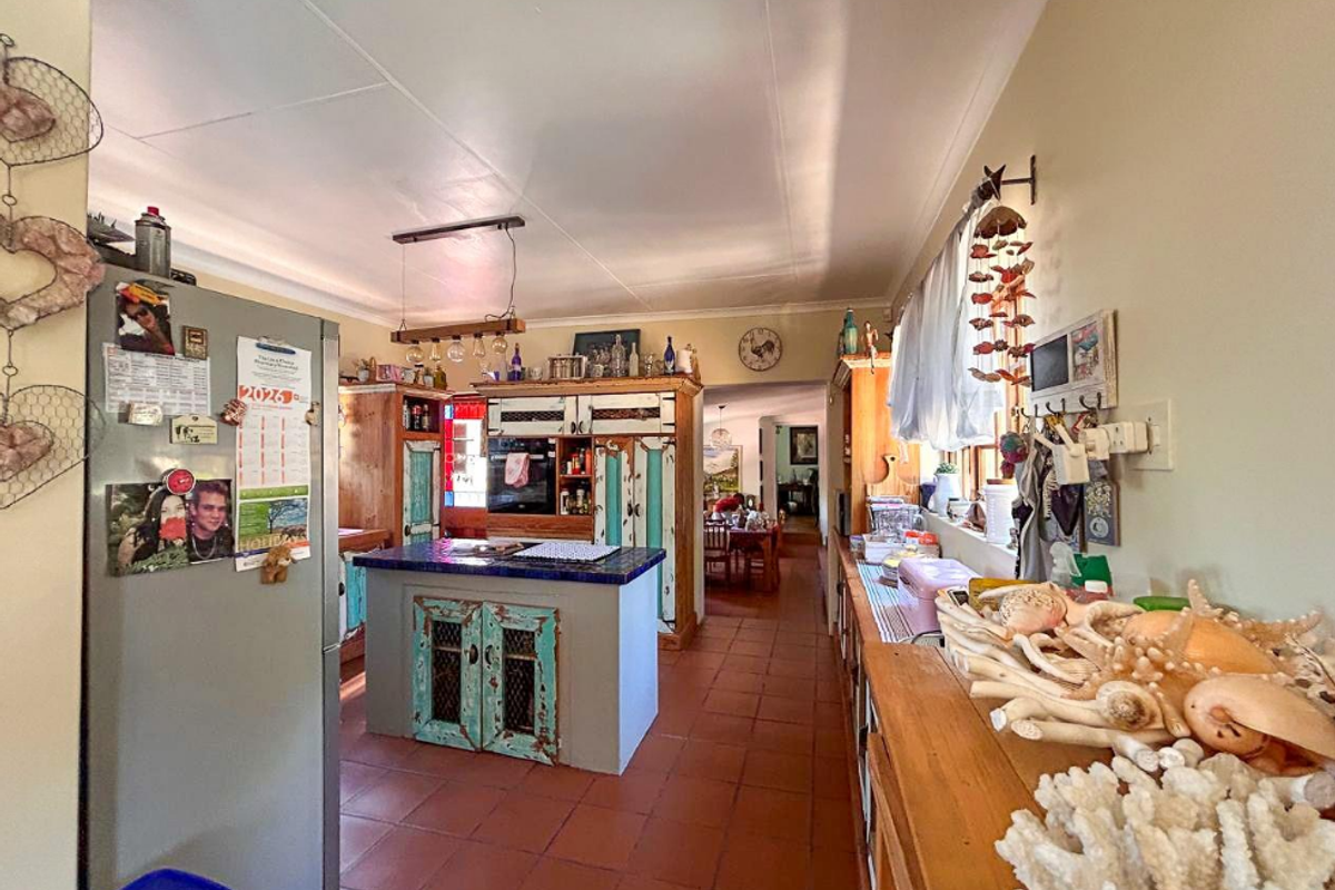 A rustic-style kitchen featuring a central island, built-in cabinetry, and terracotta tiled flooring, offering a warm and functional cooking space.