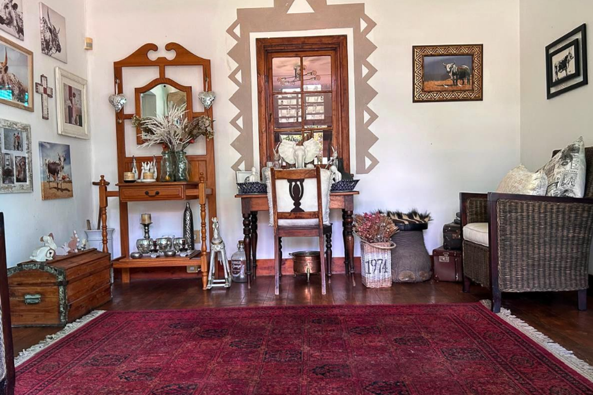 A cozy living area featuring warm timber flooring and a distinctive timber-framed window with decorative wall detailing.
