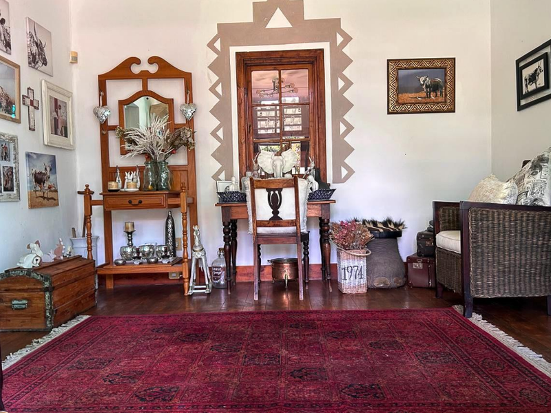 A cozy living area featuring warm timber flooring and a distinctive timber-framed window with decorative wall detailing.