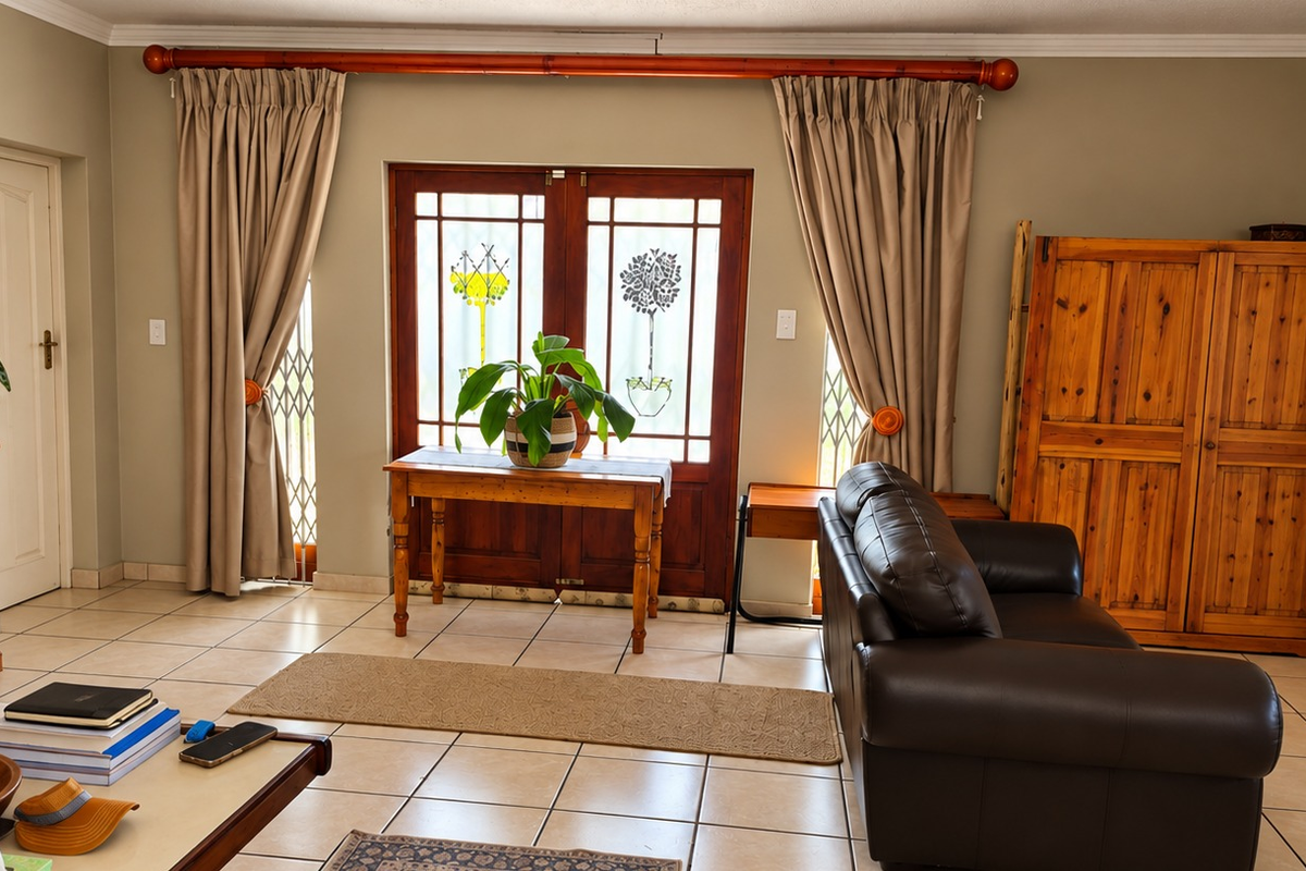 A living room featuring ceramic tiled flooring, crown molding, and wooden double doors with integrated security gates leading to the exterior.