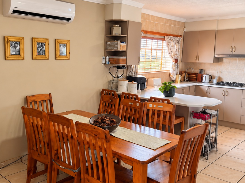Open-plan kitchen and dining area featuring tiled flooring, built-in cabinetry, gas hob, oven, and a wall-mounted air conditioning unit.