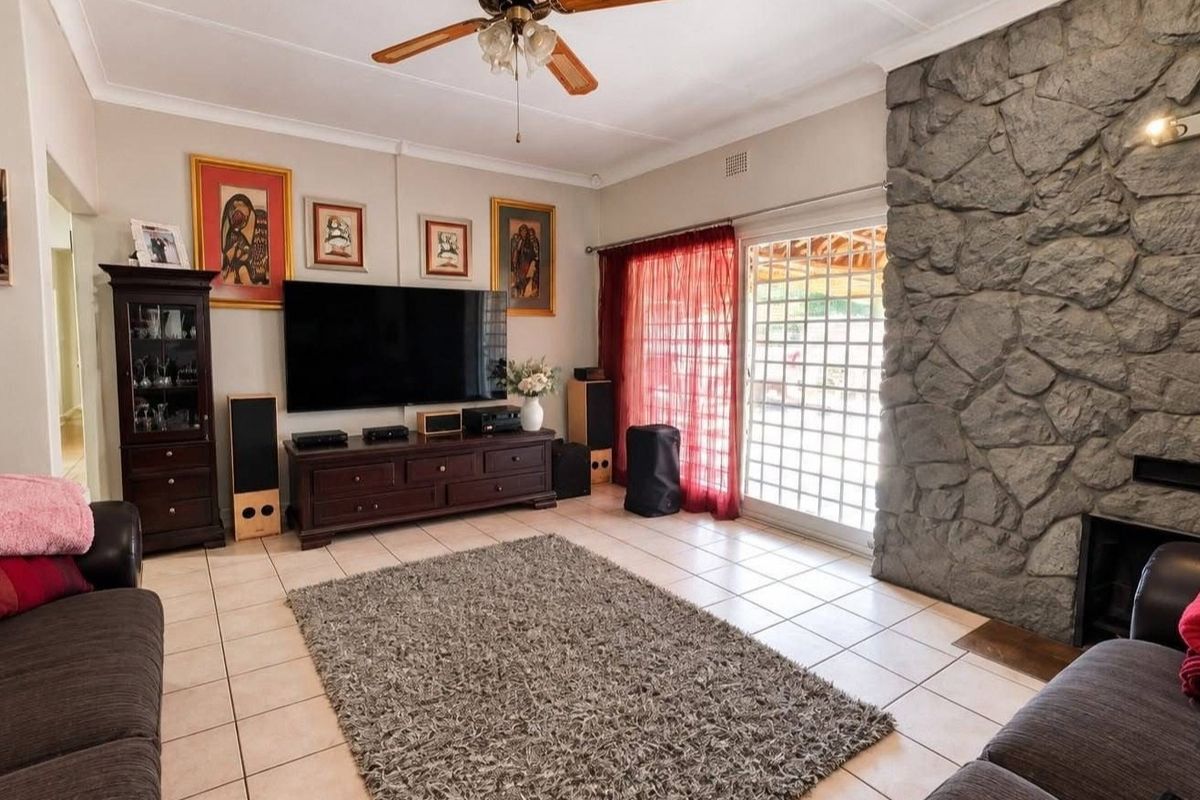 A comfortable living room featuring a prominent stone fireplace, tiled flooring, and a sliding glass door providing access to the outdoor area.