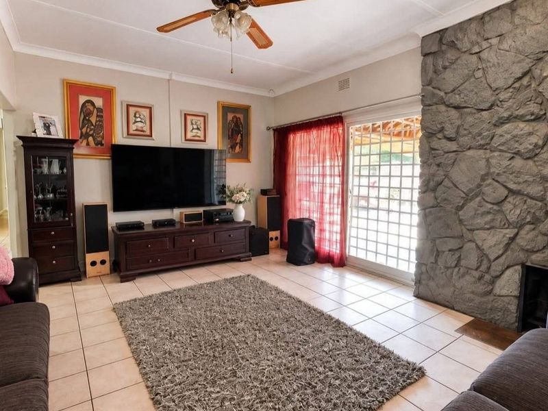 A comfortable living room featuring a prominent stone fireplace, tiled flooring, and a sliding glass door providing access to the outdoor area.
