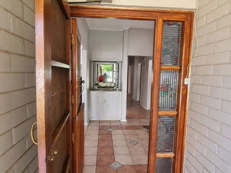 Entrance foyer featuring a timber door with leaded glass sidelight, ceramic tiled flooring, and built-in cabinetry leading into the home's hallway.