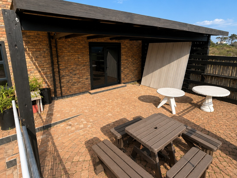 A covered outdoor patio area featuring brick paving, an exposed brick facade, and a timber pergola structure.