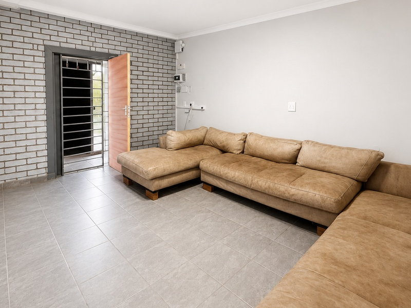 A functional office space featuring durable tiled flooring, an exposed brick feature wall, and a secure entrance with a fitted security gate.