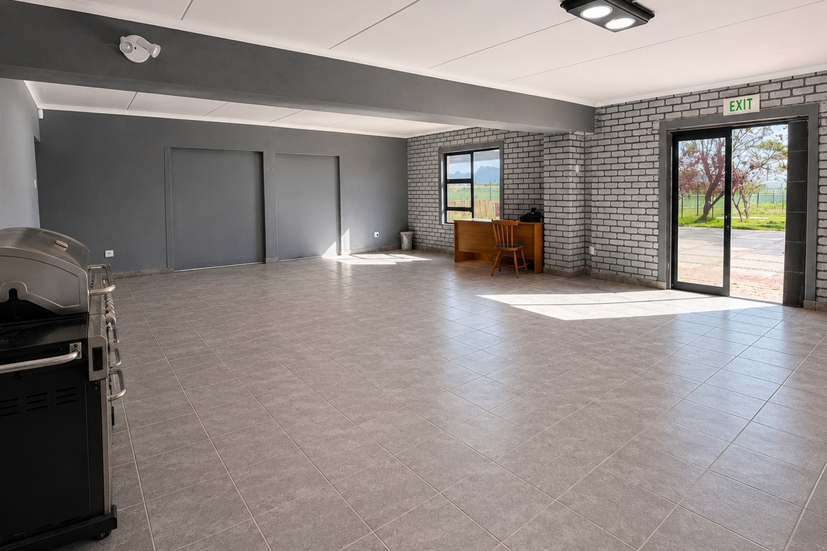 Spacious open-plan office area featuring tiled flooring, exposed brick accents, and direct access to an outdoor area through a sliding glass door.
