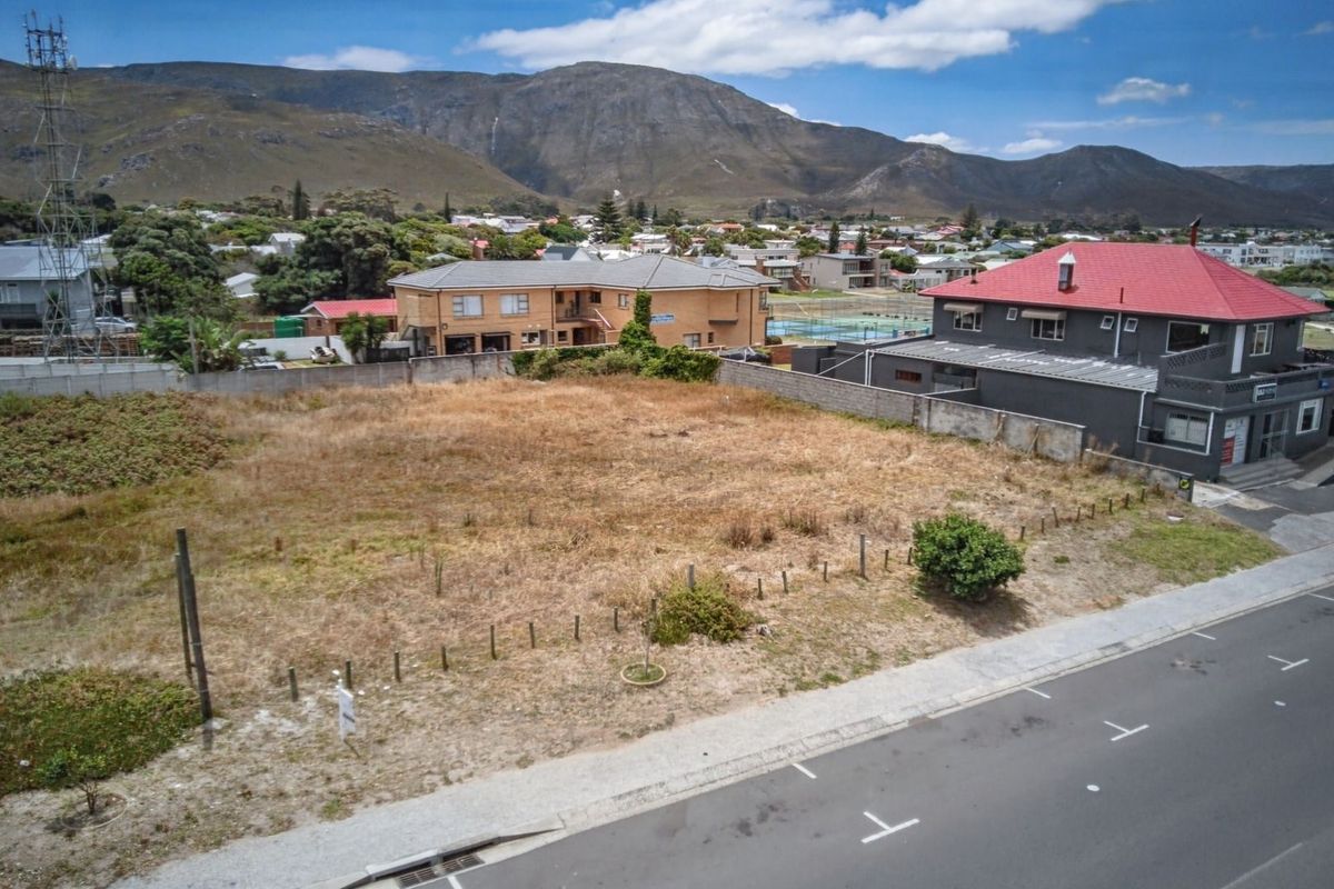 Aerial view of a vacant commercial plot situated in a developed area with mountain views and street access.