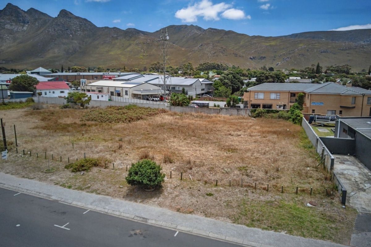 Aerial view of a vacant commercial land plot situated in a developed area with mountain views in the background.