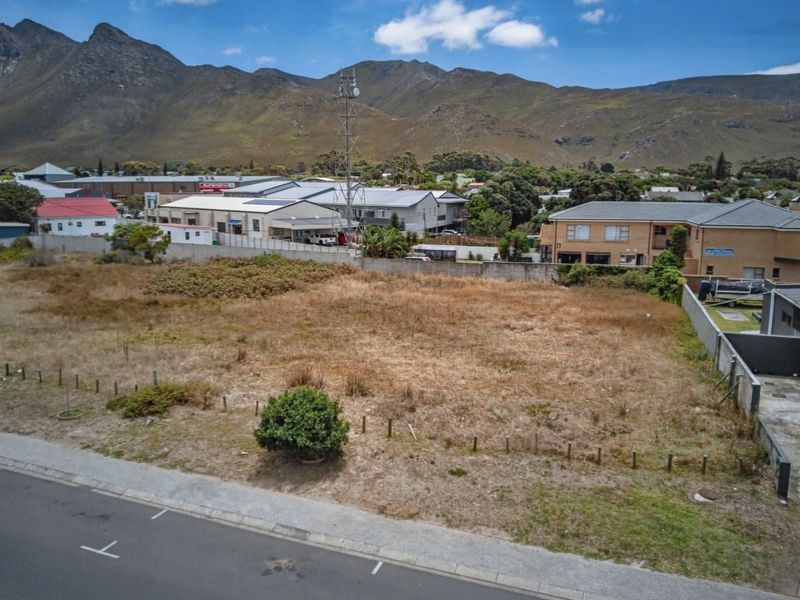 Aerial view of a vacant commercial land plot situated in a developed area with mountain views in the background.