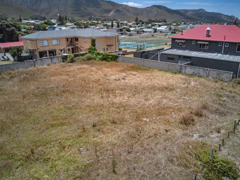 An aerial view of a vacant commercial plot featuring perimeter boundary walls and surrounding residential development.