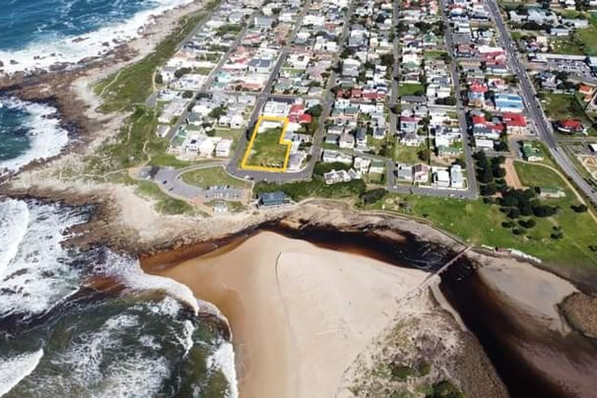 Aerial view of a vacant commercial land plot situated in a prime coastal location near the beach and residential area.