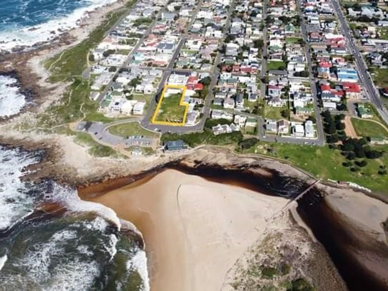 Aerial view of a vacant commercial land plot situated in a prime coastal location near the beach and residential area.