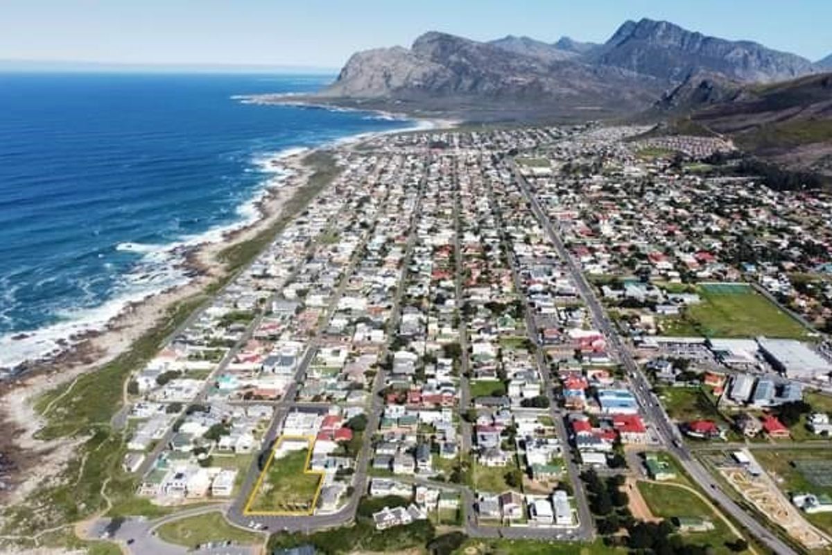 Aerial view of a vacant commercial land plot situated in a coastal neighborhood with mountain and ocean views.