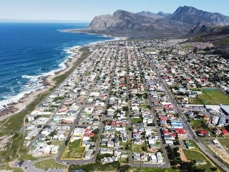 Aerial view of a vacant commercial land plot situated in a coastal neighborhood with mountain and ocean views.