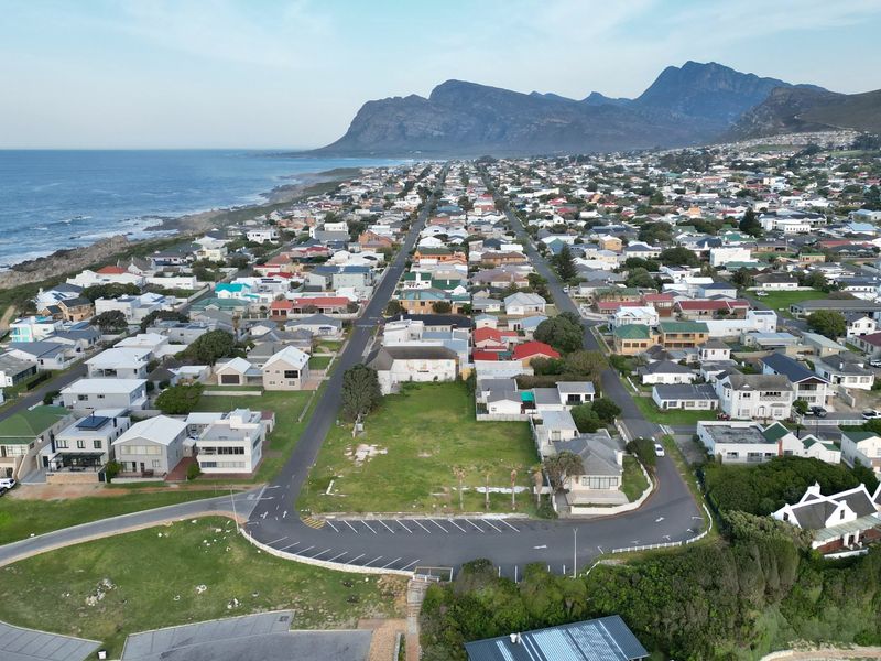 Aerial view of a vacant commercial plot situated in a coastal residential neighborhood with established infrastructure and nearby ocean access.