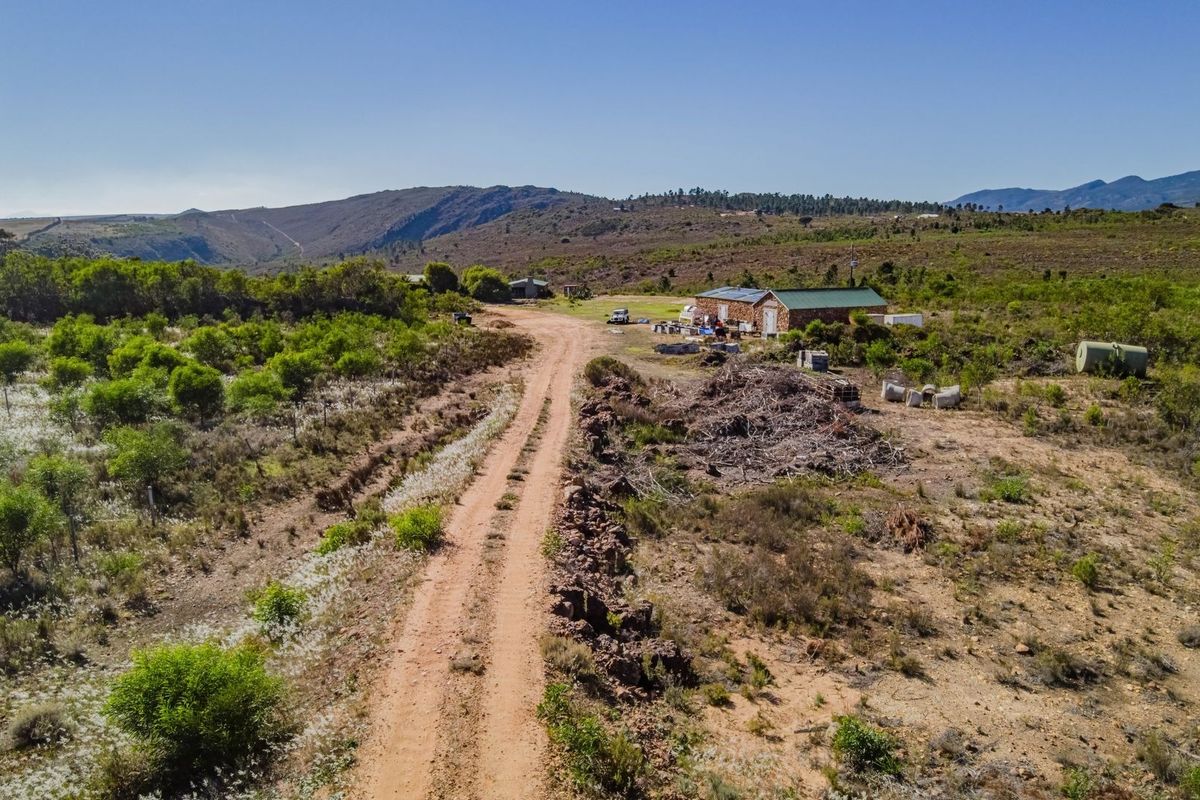 Aerial view of a large vacant commercial land plot featuring a dirt access road and an existing outbuilding structure.