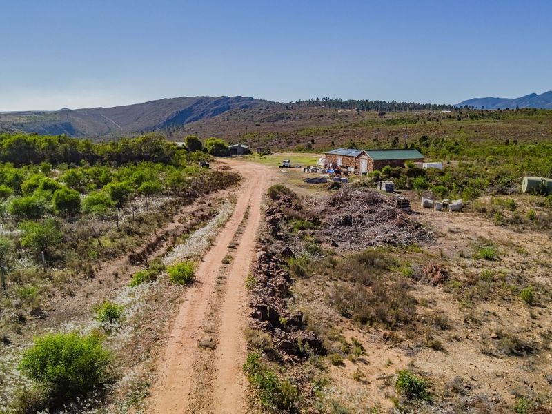 Aerial view of a large vacant commercial land plot featuring a dirt access road and an existing outbuilding structure.