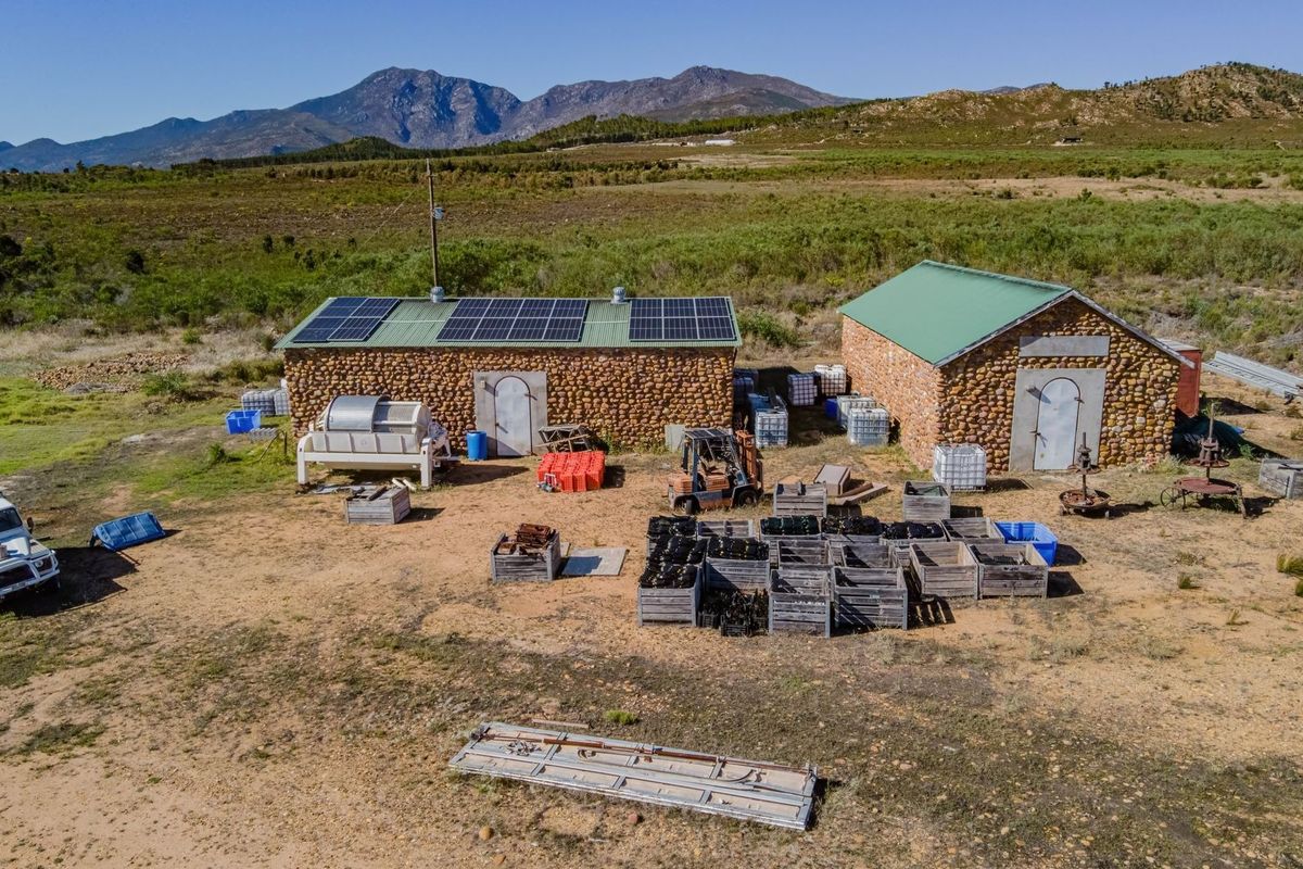 Aerial view of commercial property featuring two stone-clad utility buildings equipped with roof-mounted solar panels set within a rural landscape.
