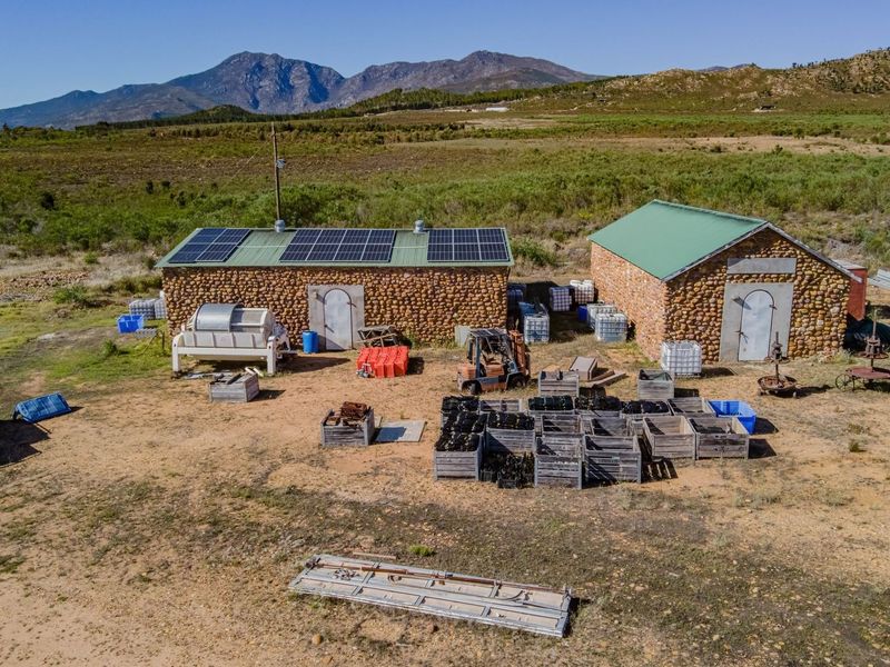 Aerial view of commercial property featuring two stone-clad utility buildings equipped with roof-mounted solar panels set within a rural landscape.