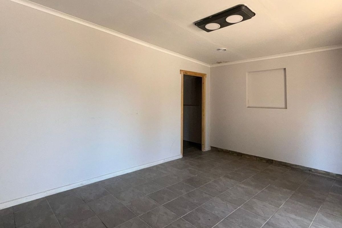 An empty, neutral-toned room featuring tiled flooring, a recessed wall niche, and a coved ceiling, ready for customization.