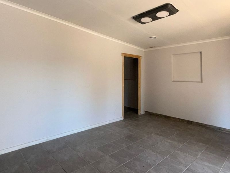 An empty, neutral-toned room featuring tiled flooring, a recessed wall niche, and a coved ceiling, ready for customization.