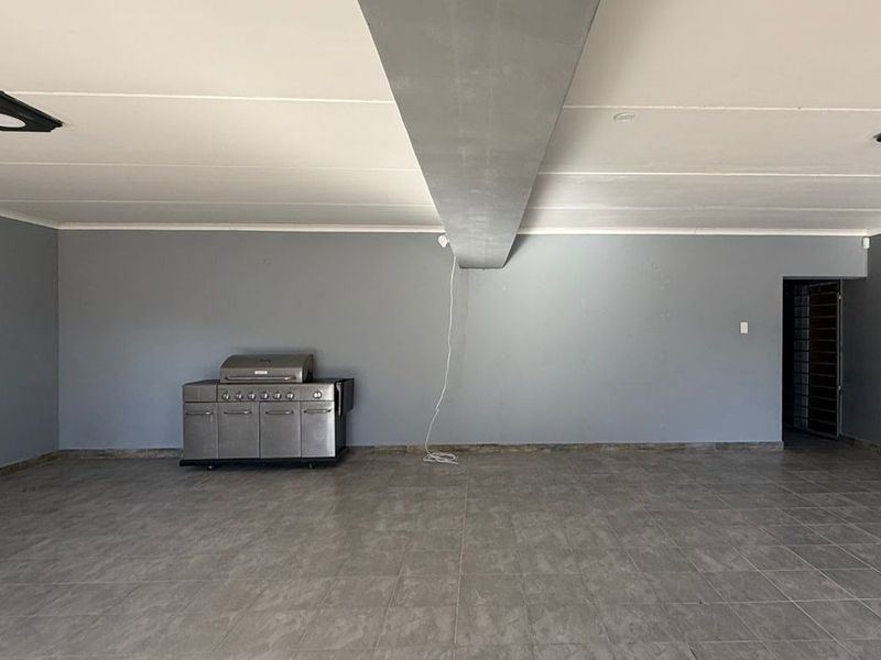 Spacious open-plan commercial area featuring neutral grey walls, durable tiled flooring, and recessed ceiling lighting, suitable for various business or retail configurations.