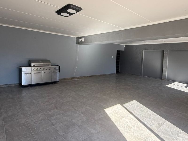 Spacious open-plan commercial area featuring neutral grey walls, tiled flooring, and recessed lighting, offering a versatile layout for various business applications.