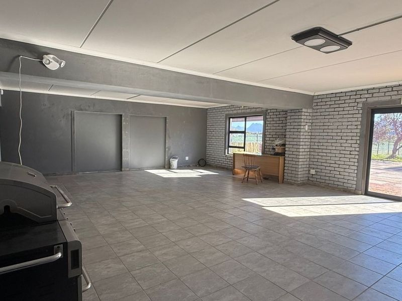 Spacious open-plan commercial area featuring tiled flooring, exposed brick walls, and large sliding glass doors providing natural light and outdoor access.