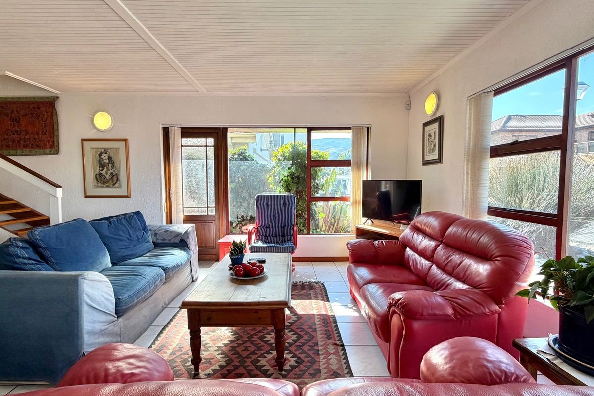 Spacious living room featuring tiled flooring, a staircase, and large windows that provide ample natural light and garden views.