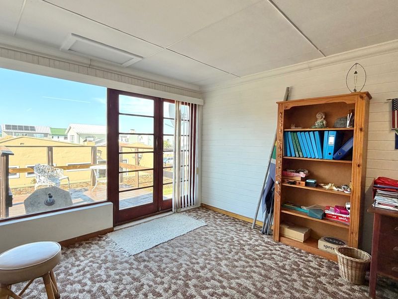 A living area featuring large windows and sliding doors that provide natural light and access to an outdoor deck area.