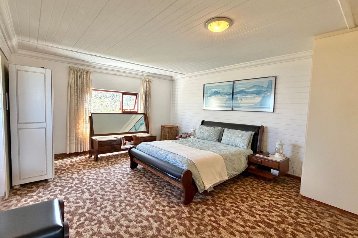 Spacious bedroom featuring timber panelled walls and ceiling, carpeted flooring, and a large window allowing natural light.