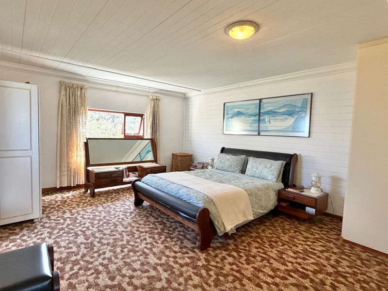 Spacious bedroom featuring timber panelled walls and ceiling, carpeted flooring, and a large window allowing natural light.