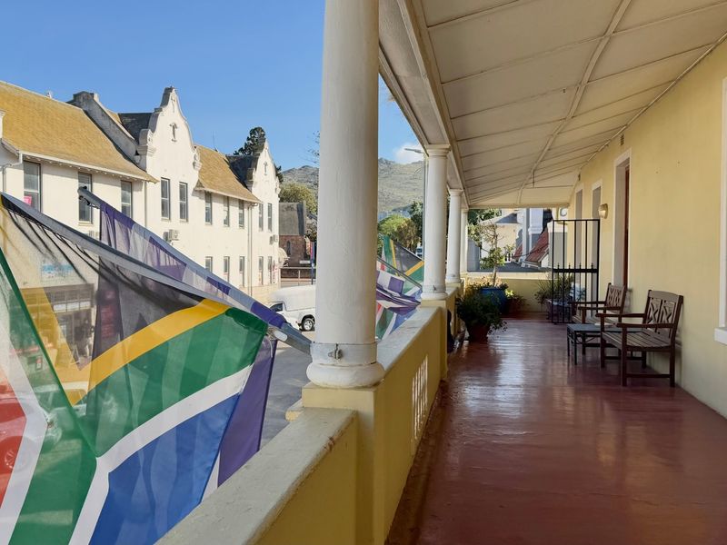 A covered balcony featuring classic columns and a painted floor, offering an outdoor space with views of the surrounding streetscape.